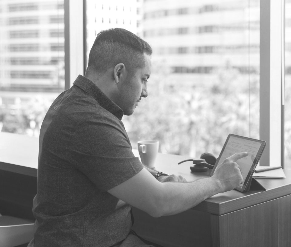 A black and white photo of a man engaged with his iPad, illustrating modern technology and productivity.